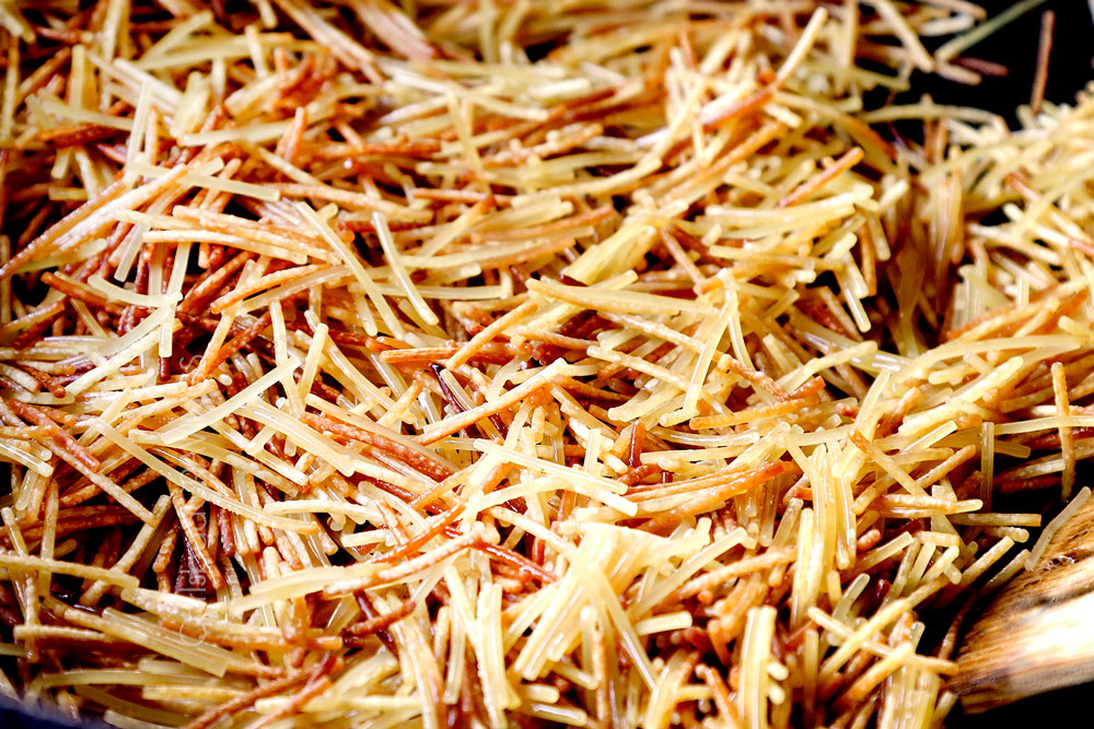 showing how to make fideo by browning fideo pasta in a sillet