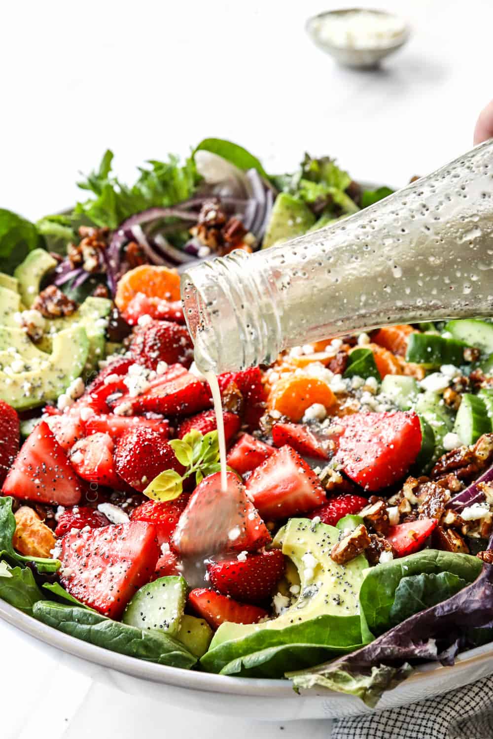 showing how to make strawberry spinach salad recipe by dressing with poppy seed vinaigrette