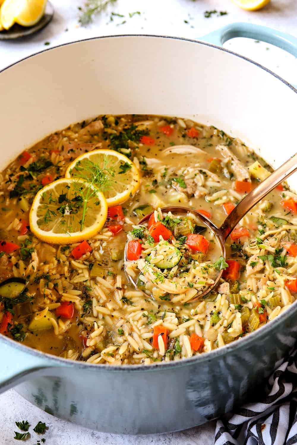 Greek lemon chicken orzo soup in a Dutch oven with fresh dill