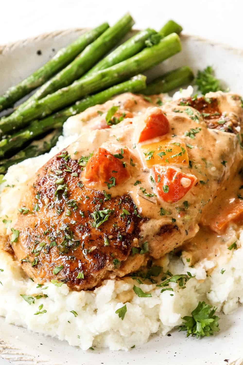 up close of a piece of Cajun chicken on a plate with mashed potatoes and asparagus