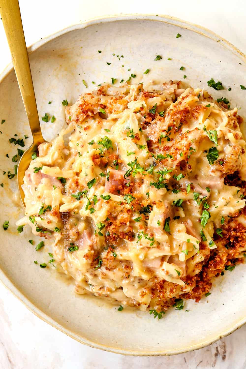 top view of chicken cordon bleu casserole with ham and potatoes on a plate topped with panko and parsley