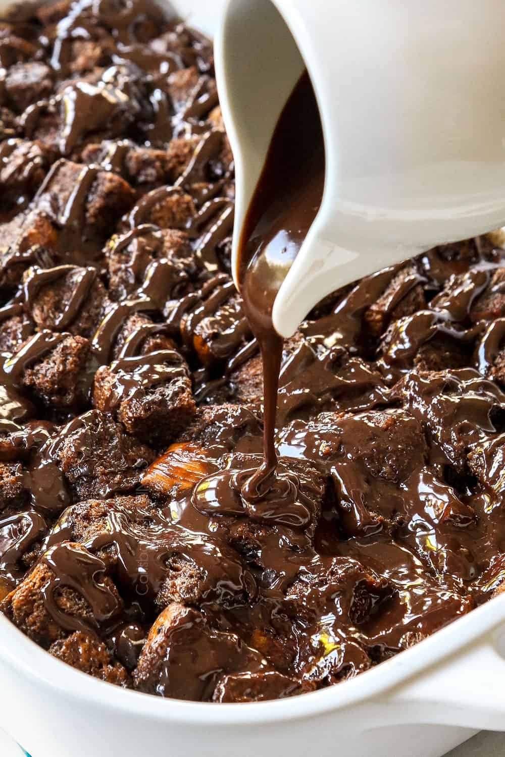 showing how to make bread pudding recipe by drizzling chocolate ganache over baked chocolate bread pudding