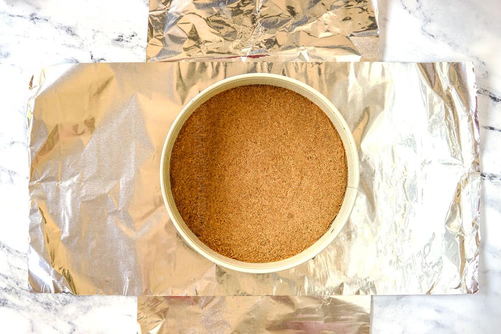 showing how to waterproof pan by laying foil out in two pieces underneath the spring form pan