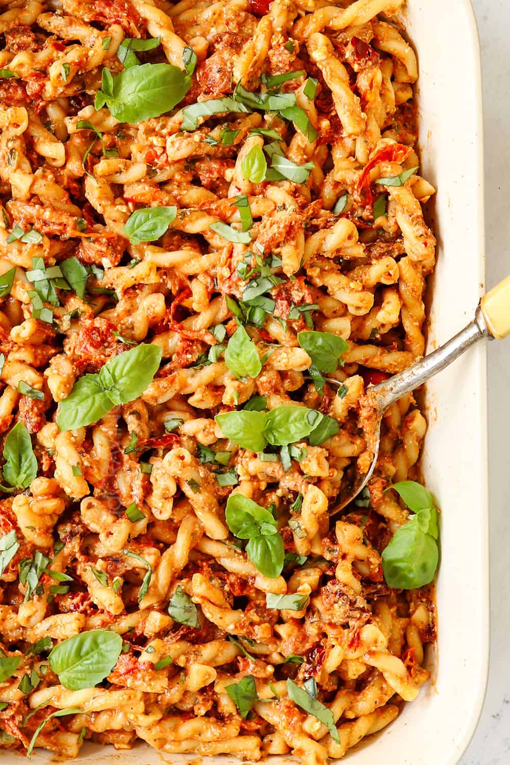 showing how to make TikTok Baked Feta Pasta by garnishing the dish with basil