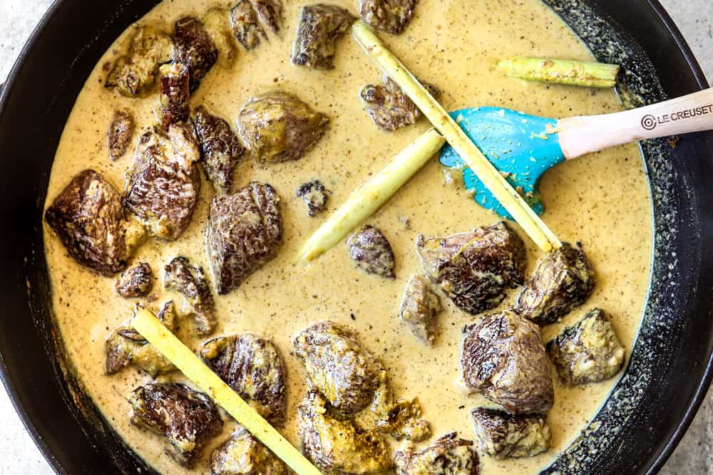showing how to make beef rendang by adding beef, lemongrass, curry paste and coconut milk to a Dutch oven to simmer
