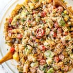 showing how to make Mexican Pasta salad by tossing the dressing and the ingredients together in a glass bowl