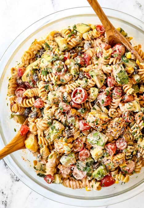 showing how to make Mexican Pasta salad by tossing the dressing and the ingredients together in a glass bowl