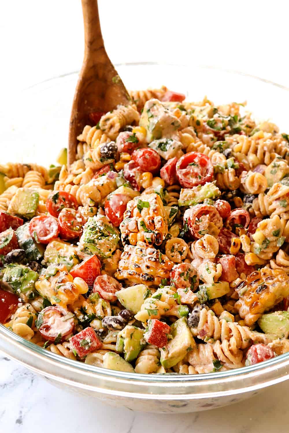 tossing Mexican pasta salad together in a glass bowl