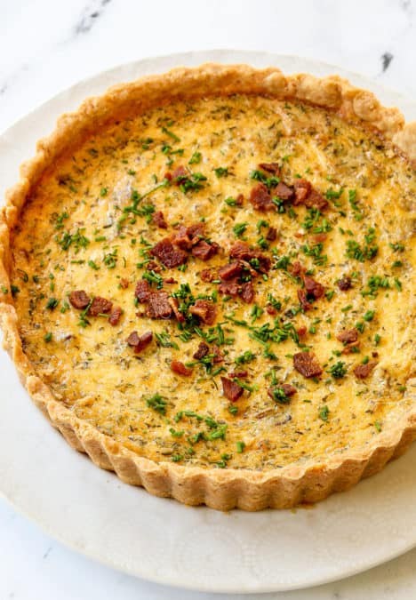 top view of Quiche Lorraine garnished with chives on a white plate