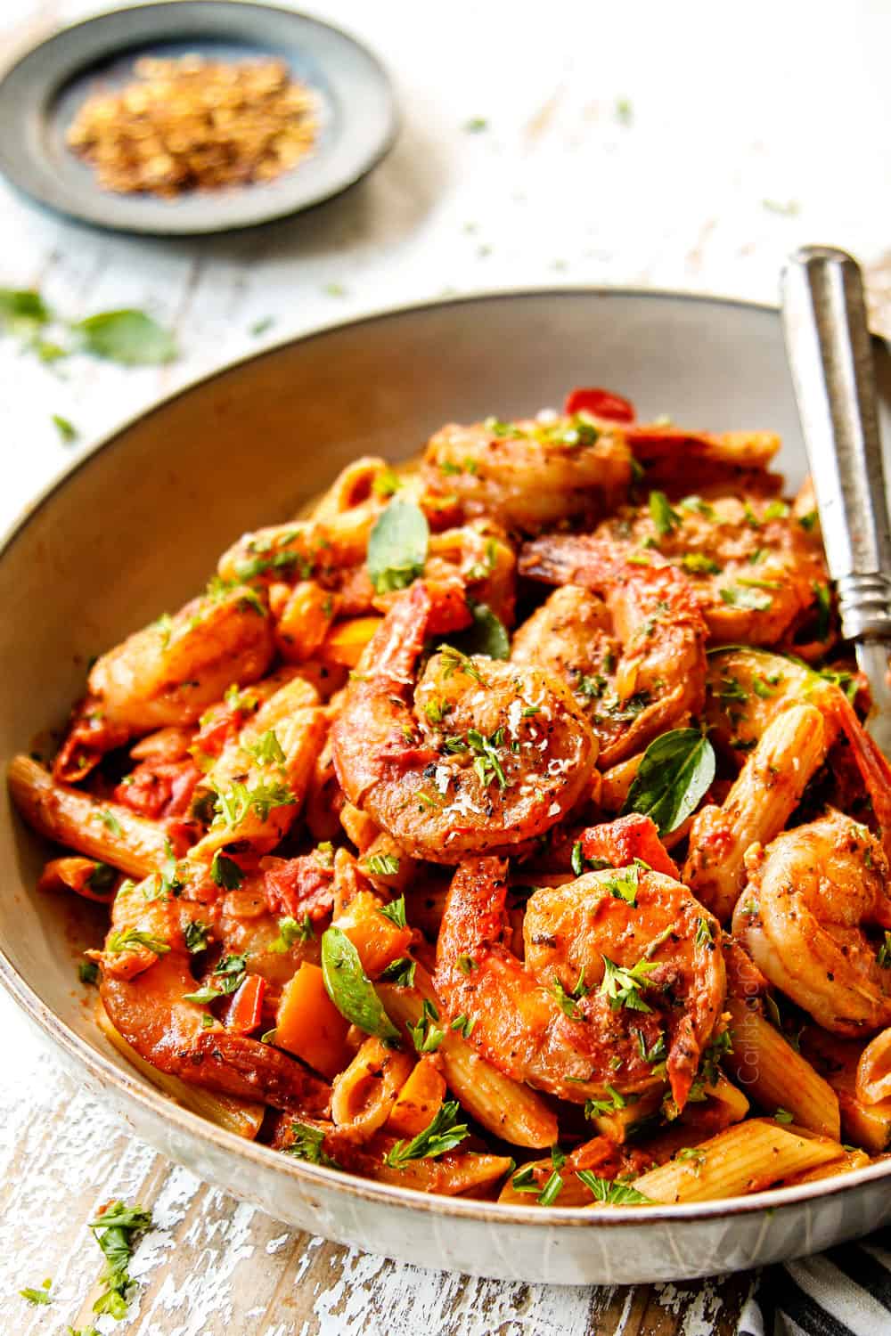 showing how to make shrimp pasta by adding to a bowl
