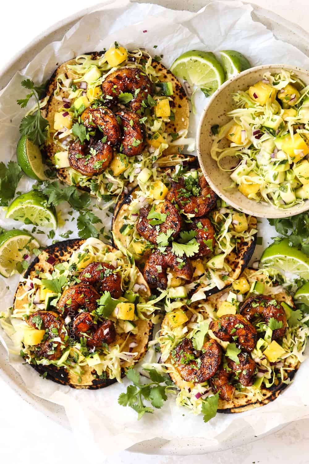 top view of spicy shrimp tacos with slaw on a white platter