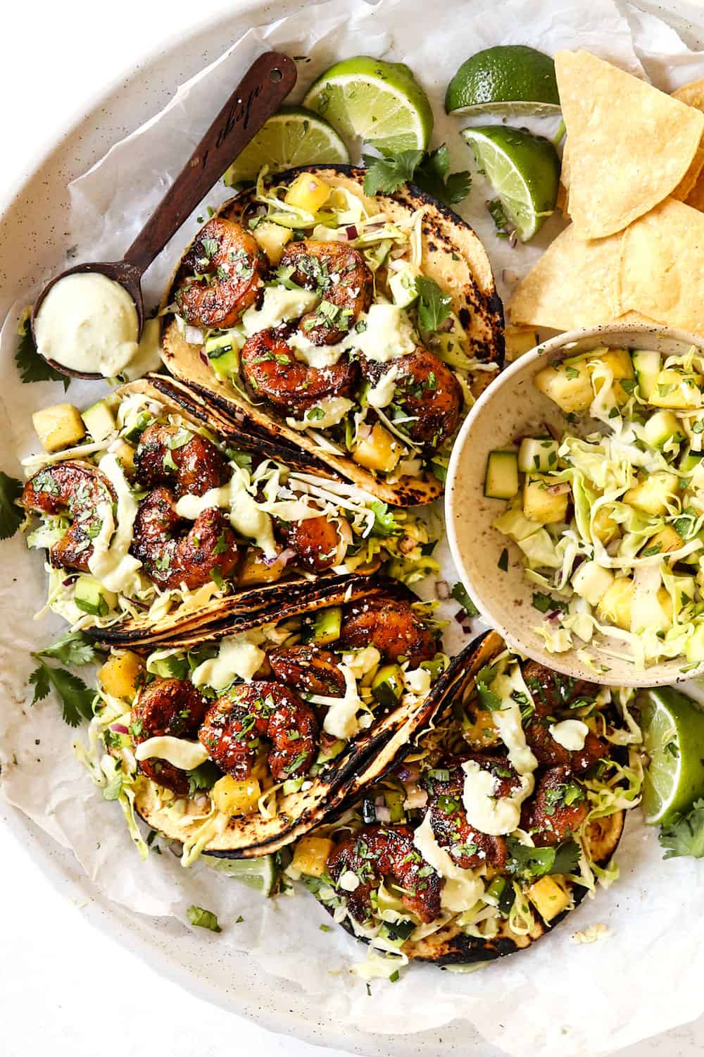 showing how to serve easy spicy shrimp taco recipe by lining tacos on a white platter