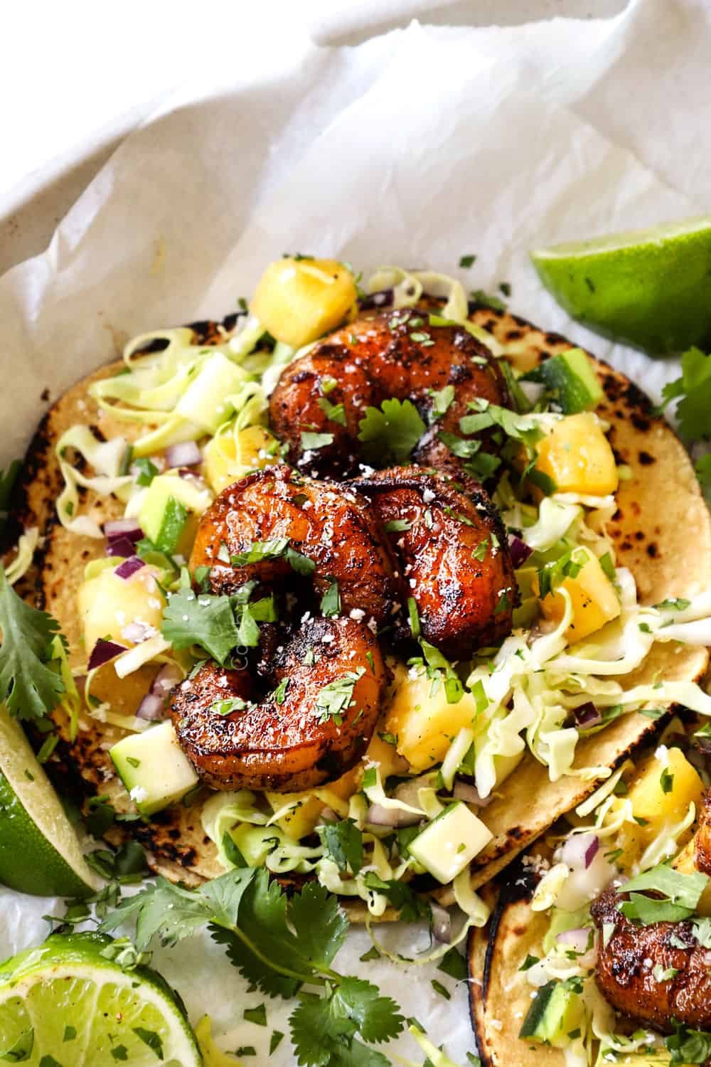 showing how to make spicy shrimp taco recipe by adding slaw and shrimp to a tortilla