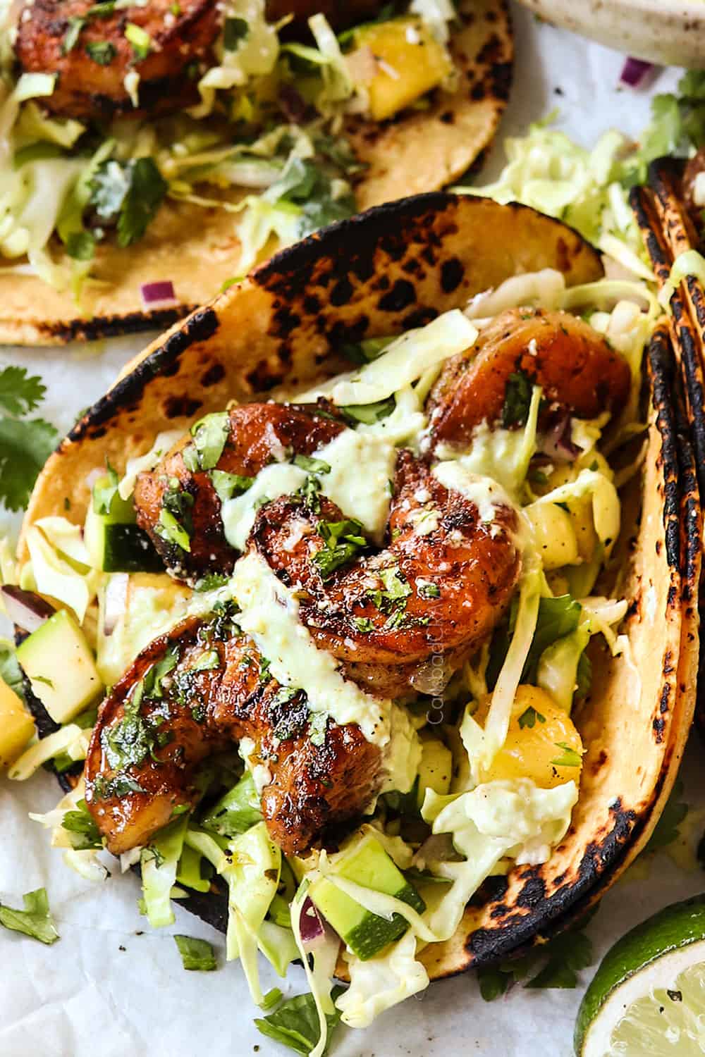 up close of showing how to make shrimp taco recipe by drizzling with avocado crema