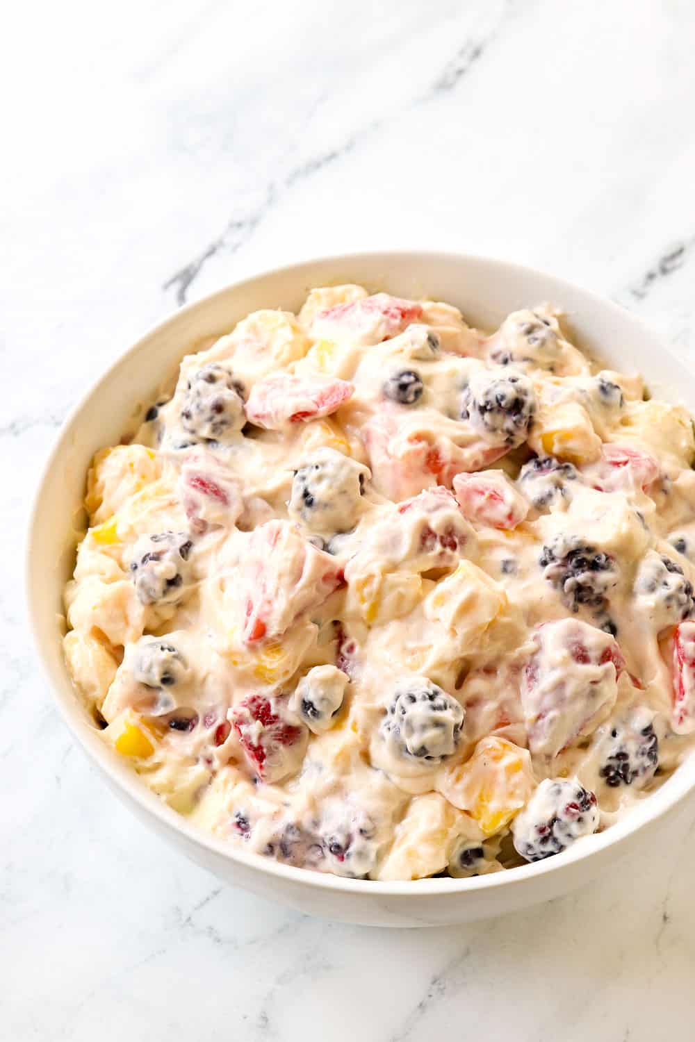 cheesecake salad in a bowl with strawberries, bananas, blackberries and pineapple