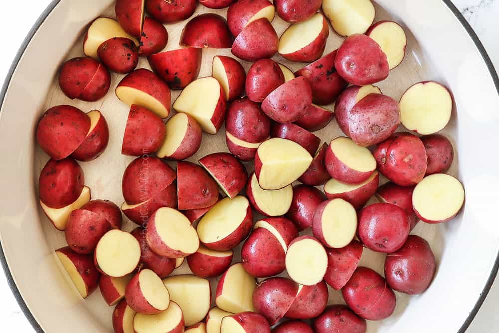 showing how to make German potato salad recipe by boiling potatoes in a white Dutch oven