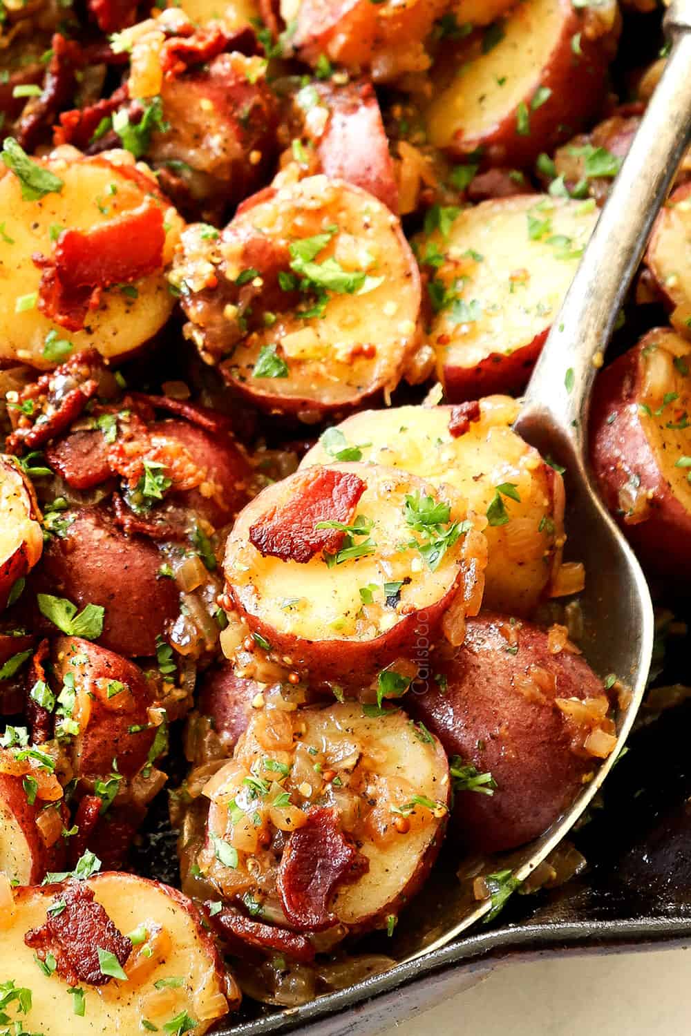 up close of a spoonful of German potato salad showing how crispy the bacon is
