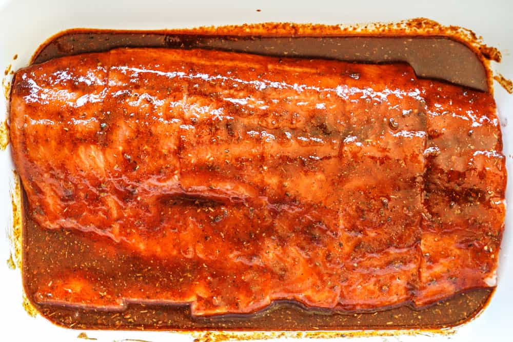 showing how to grill salmon by marinating salmon in a marinade in a 9x13 dish