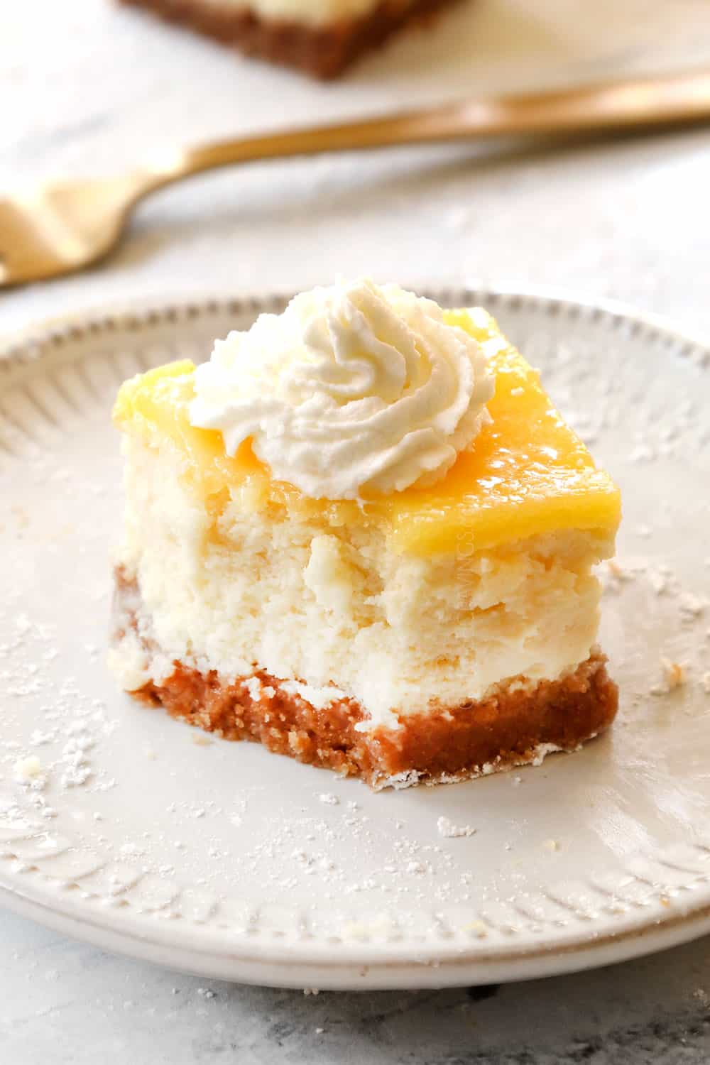 up close of lemon cheesecake bar with a bite out of showing how creamy it is
