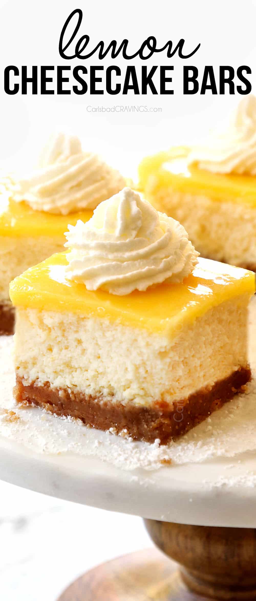 up close of lemon cheesecake bars with whipped cream on a cake pedestal