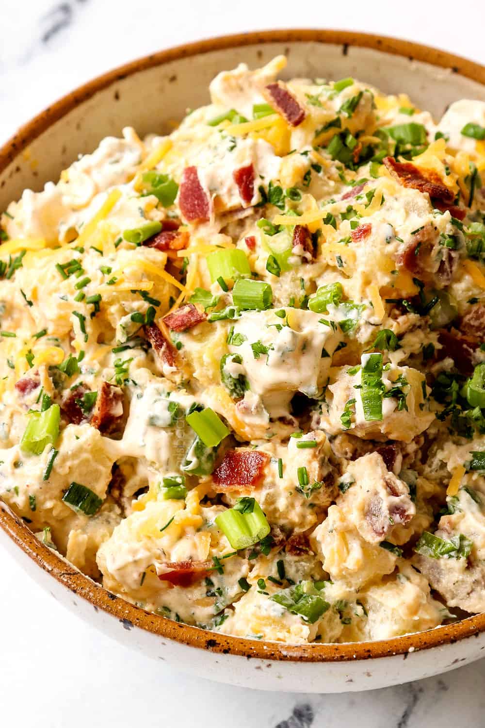 up close of creamy potato salad with bacon and chives in a bowl