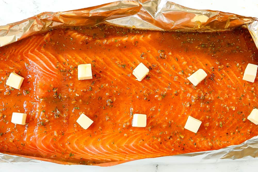 showing how to make grilled salmon in foil by adding butter to the top of the salmon