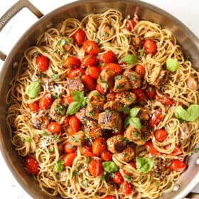 top view of bruschetta chicken pasta recipe with chicken, tomatoes and basil