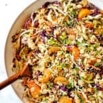top view showing how to make Asian Ramen Noodle Salad by tossing the ingredients together with the dressing in a white bowl