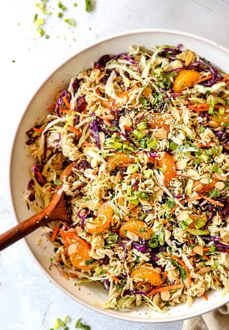top view showing how to make Asian Ramen Noodle Salad by tossing the ingredients together with the dressing in a white bowl