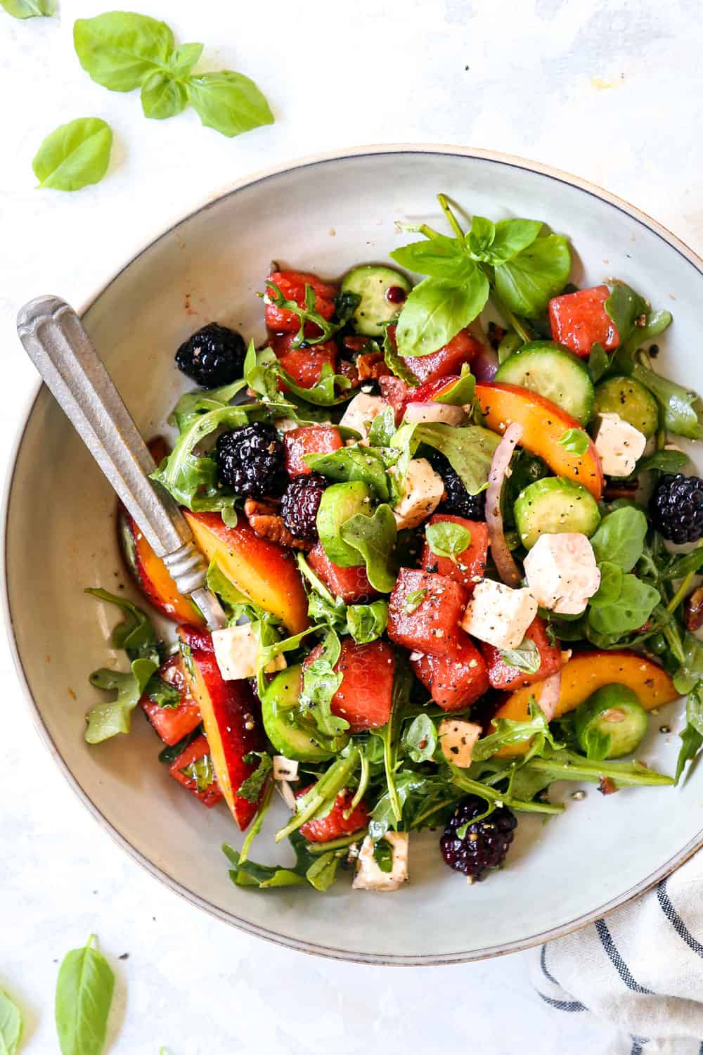 top view of watermelon feta salad with basil, cucumbers and arugula