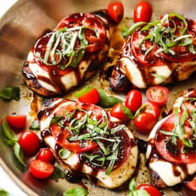 showing how to make chicken caprese by adding basil to chicken in the skillet