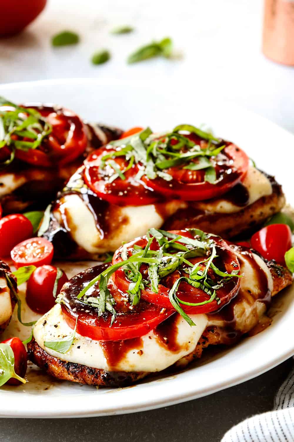 up close of chicken Caprese showing how cheesy it is layered with mozzarella cheese, tomato slices, basil and balsamic reduction