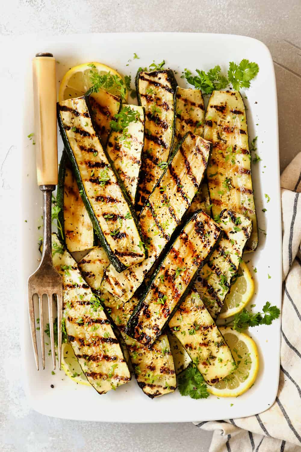top view of grilled zucchini and squash on a white platter with distinct grill marks
