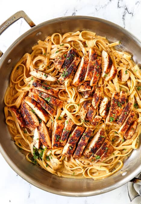 showing how to serve blackened chicken by adding chicken to blackened chicken alfredo