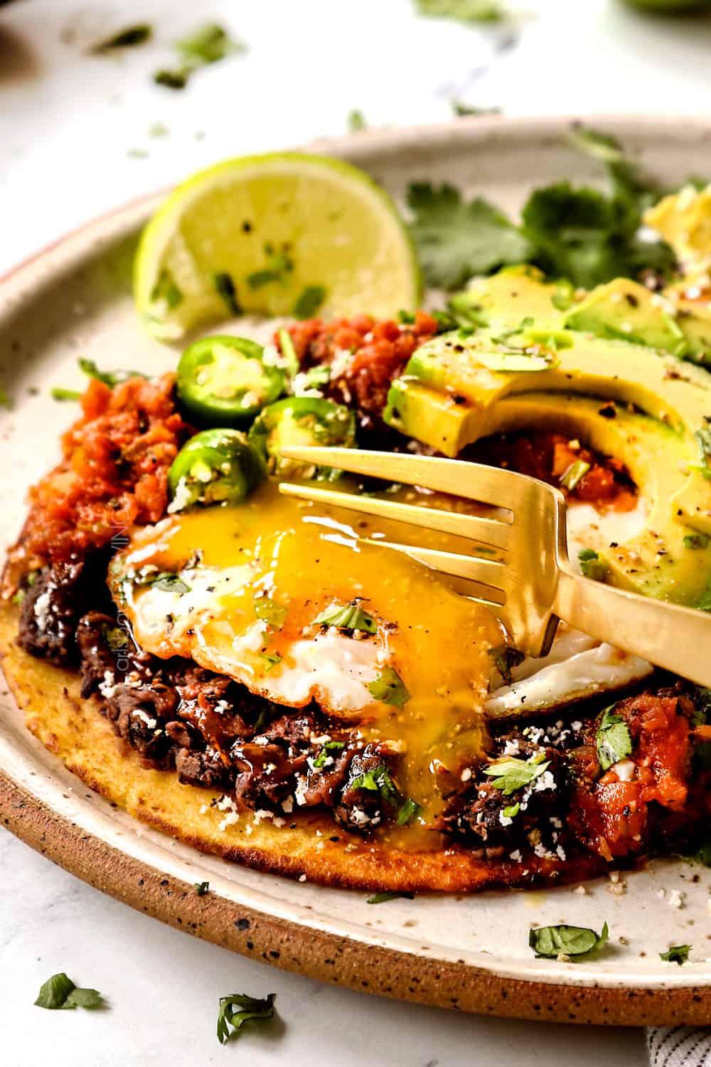 showing how to eat Huevos Rancheros by cutting the egg yolk so it runs into the salsa creating a sauce