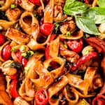 up close of Thai Drunken Noodles (Pad Kee Mao) in a with Thai bird's eye chilies, Thai basil, fresh wide rice noodles in a skillet