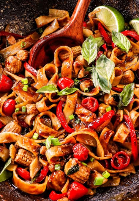 stir frying showing how to make Drunken Noodles (Pad Kee Mao) by tossing the wide rice noodles with the sauce