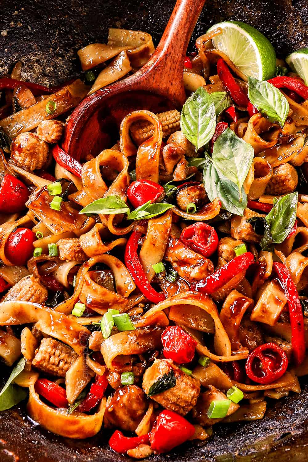 stir frying showing how to make Drunken Noodles (Pad Kee Mao) by tossing the wide rice noodles with the sauce