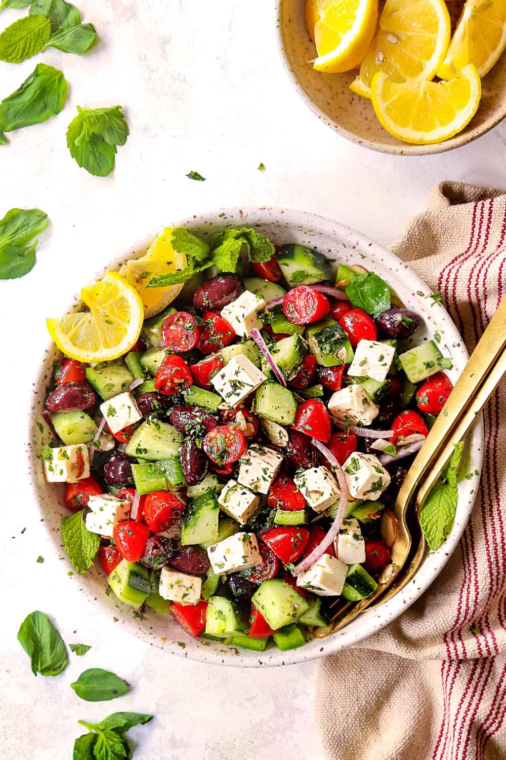 top view of showing how to make Greek Salad recipe by mixing tomatoes, cucumbers, Kalamata olives, red onions and feta together