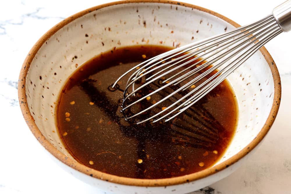 showing how to make teriyaki chicken stir fry by whisking the teriyaki sauce together in a bowl