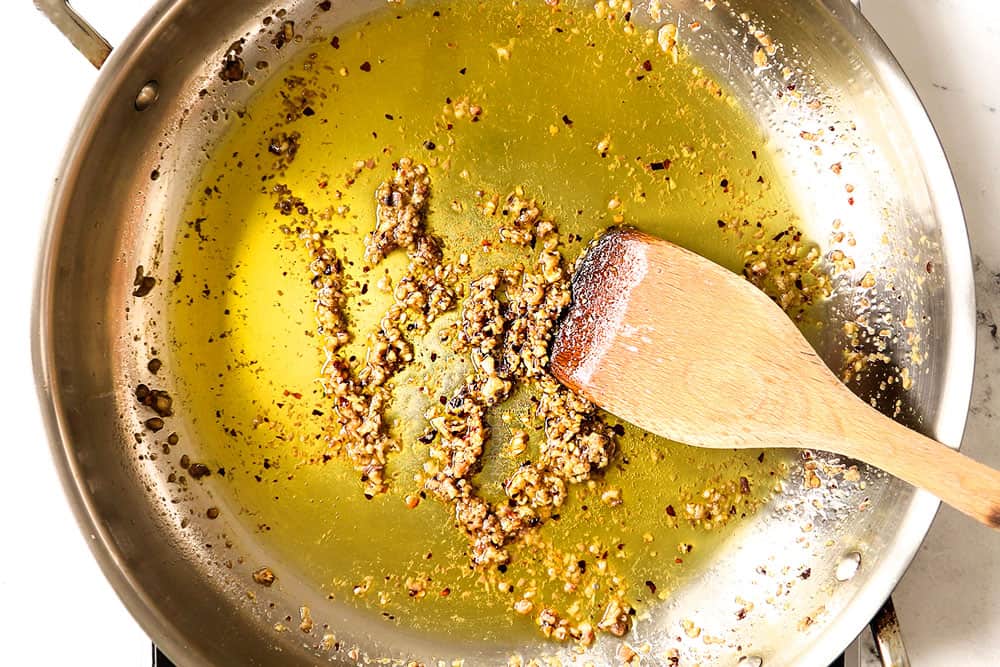 showing how to make Puttanesca recipe by sautรฉing the garlic, red pepper flakes and anchovies in olive oil