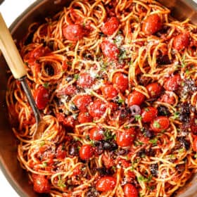 top view of pasta Puttanesca with capers, Kalamata olives and anchovies in a stainless steel skillet