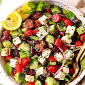 top view of showing how to make Greek Salad recipe by mixing tomatoes, cucumbers, Kalamata olives, red onions and feta together