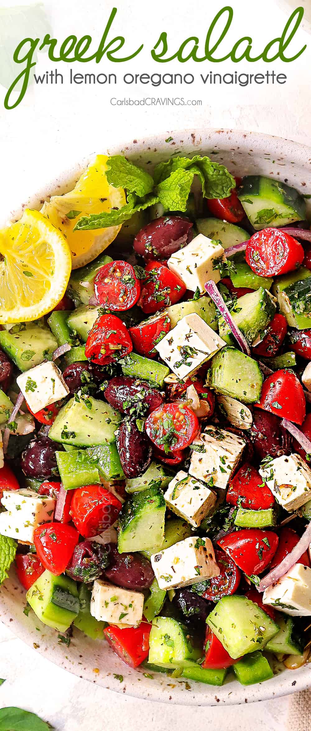 showing how to make Greek Salad recipe by mixing tomatoes, cucumbers, Kalamata olives, red onions and feta together