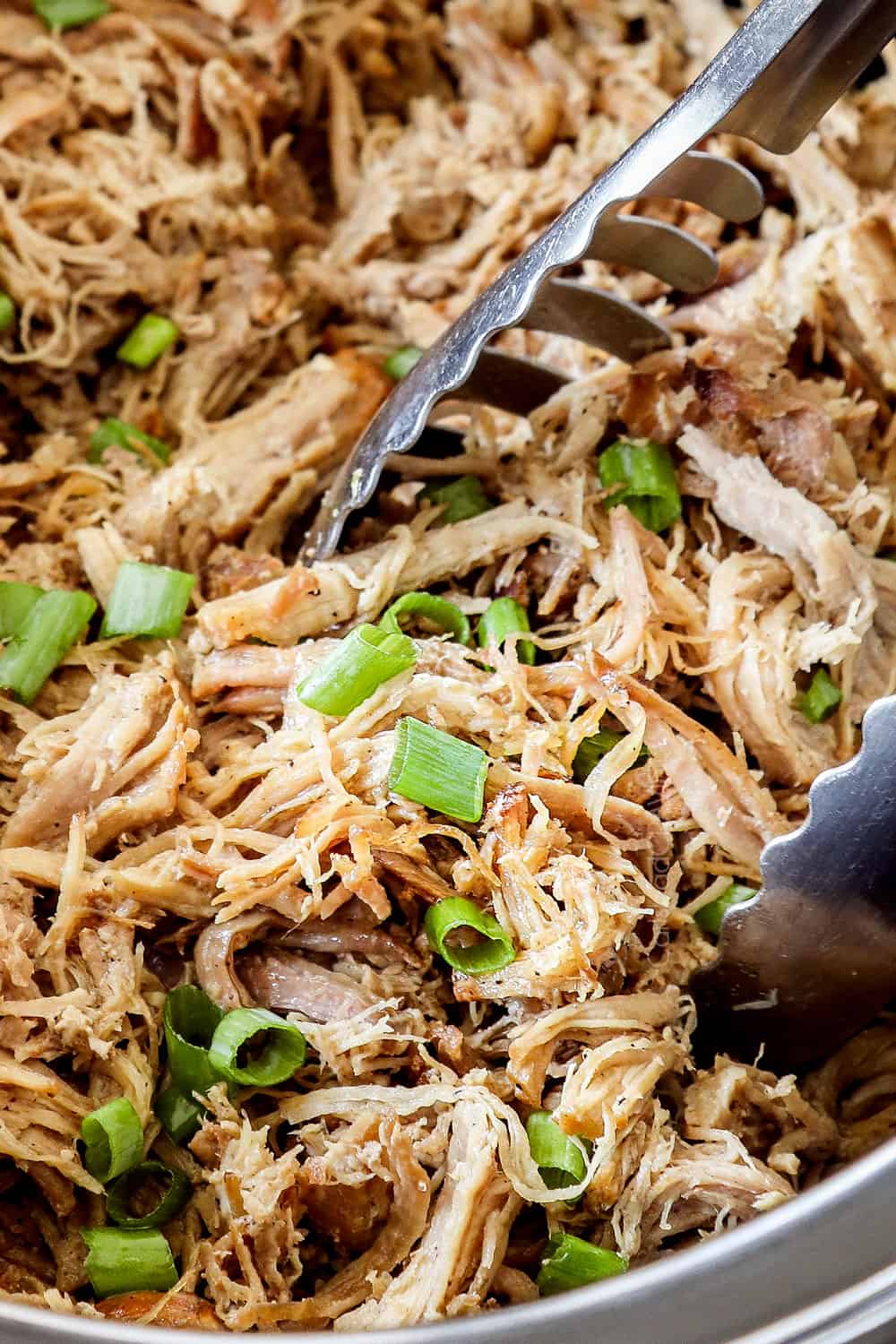 showing how to serve Kalua pork by picking it up with tongs in the slow cooker