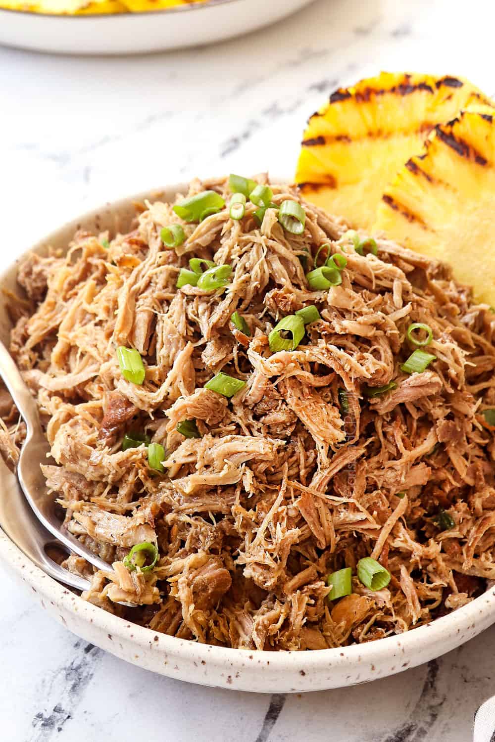 a bowl of Kalua pork recipe garnished with green onions