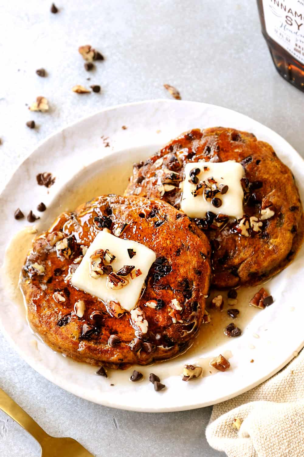two pumpkin spice pancakes on a plate with maple syrup