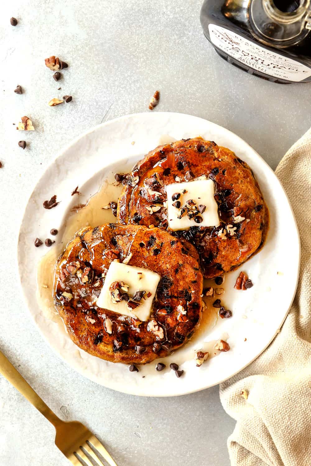 top view of two pumpkin spice pancakes on a plate with maple syrup