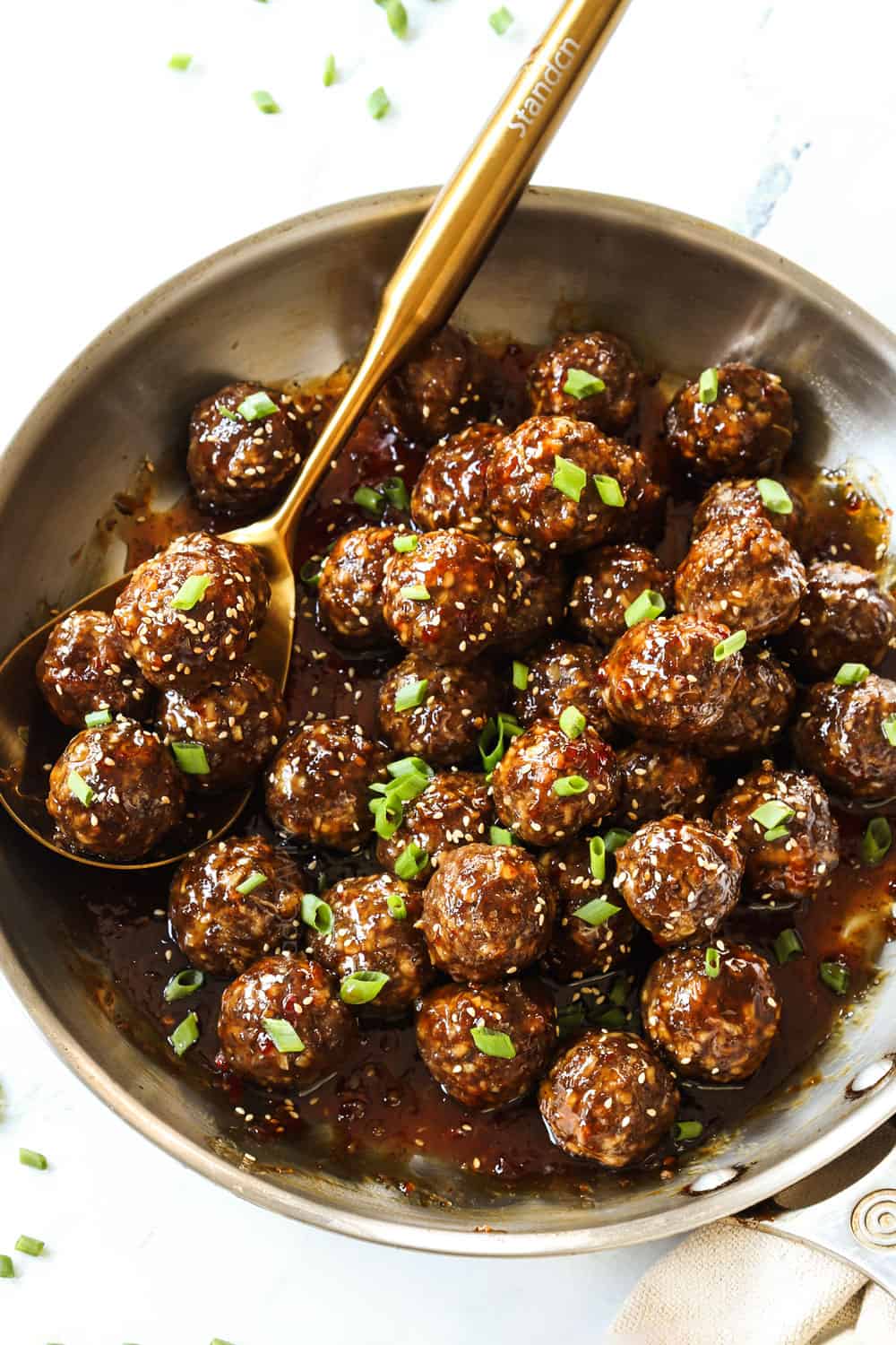 showing how to make teriyaki meatball recipe by adding the meatballs to the teriyaki sauce and stirring to combine