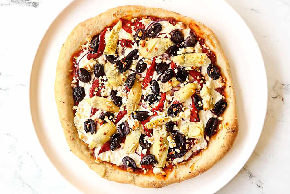 showing how to make Greek pizza recipe by baking until the crust is golden and the cheese is melted